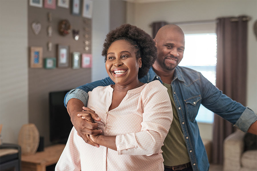Individual Life and Health Insurance - Portrait of a Cheerful Middle Aged Woman Having Fun Dancing wiith Her Husband at Home in the Living Room